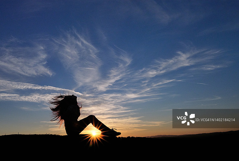 坐着观看日落的年轻女孩剪影图片素材