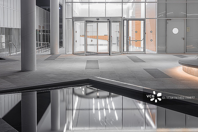 夜晚的现代建筑，夜晚办公楼入口在水池中的倒影图片素材