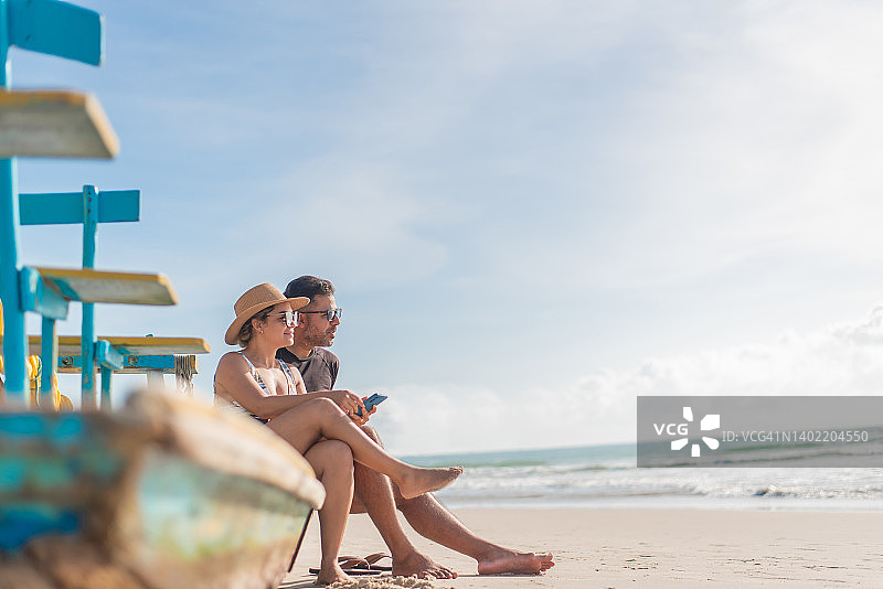 情侣在海滩上使用智能手机图片素材