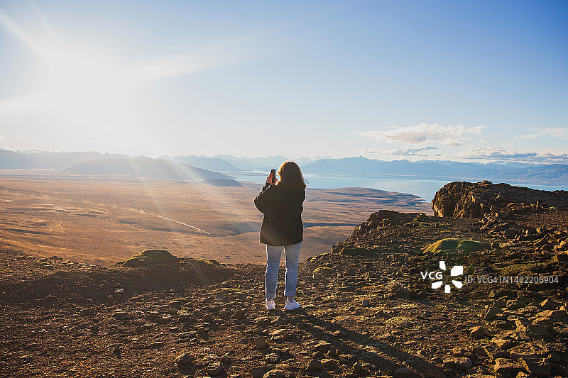 女孩用手机拍摄山谷景色图片素材