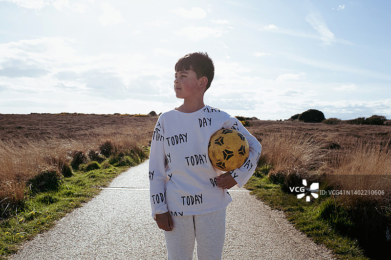 在阳光明媚的夏日户外拿着足球的亚洲男孩图片素材