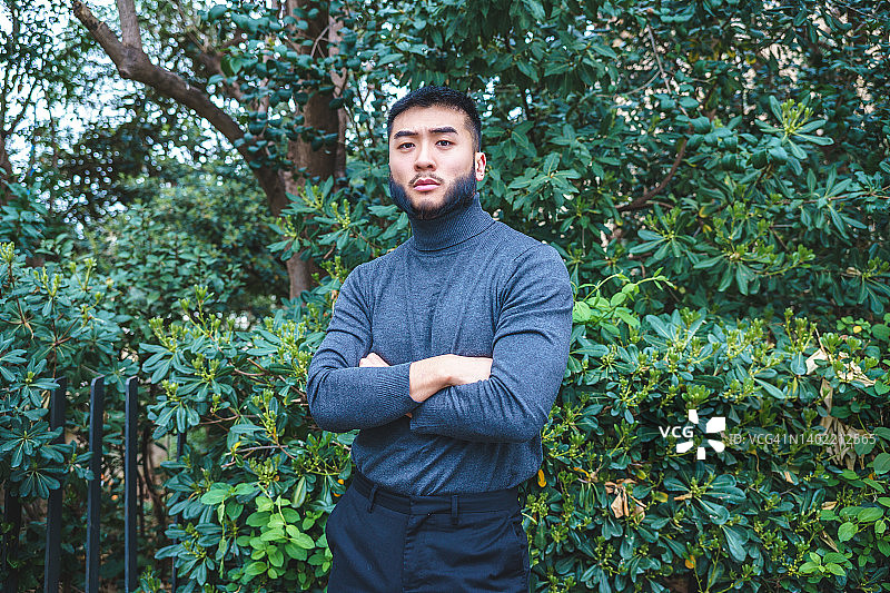公园里站在绿色灌木丛旁自信的少数民族男人图片素材
