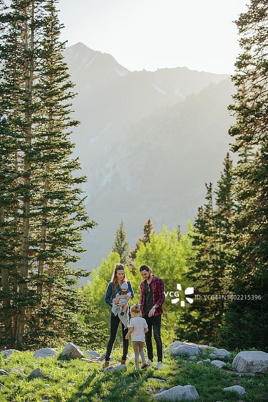 一家人在大自然中与孩子和婴儿玩耍，背景是树木和山脉图片素材
