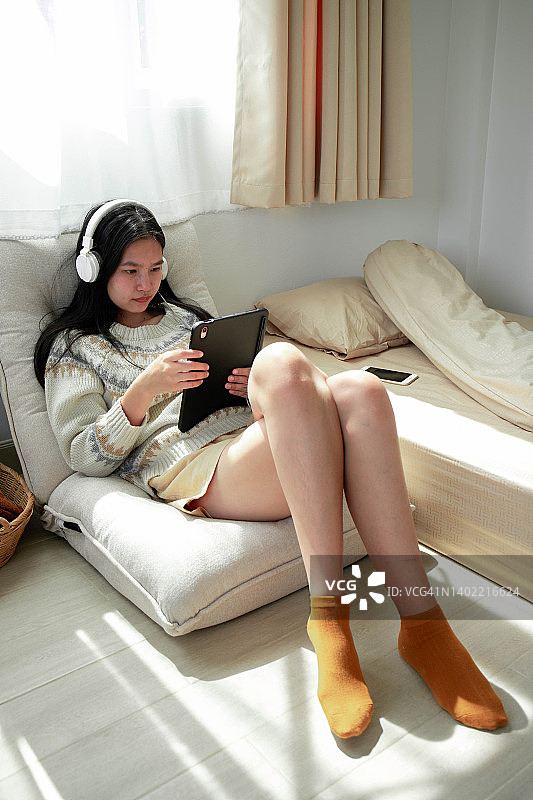 女人躺在沙发上玩iPad图片素材