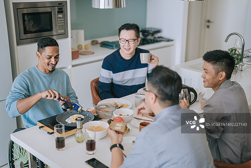 坐轮椅的印度裔男子在公寓厨房为朋友做早餐图片素材
