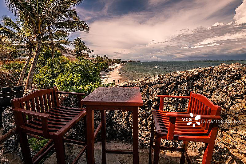 肯尼亚蒙巴萨尼亚利海滩：海滩和大海上的两把椅子和一张桌子，印度洋日落图片素材