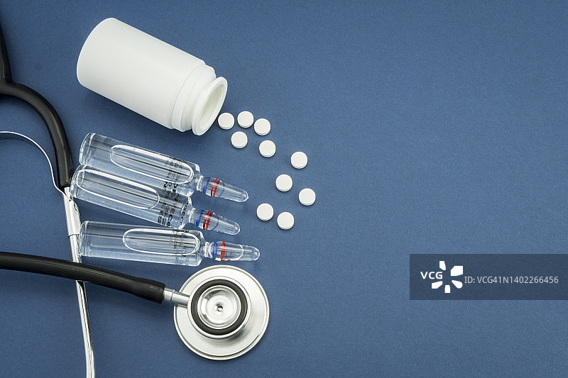 洒落的药丸和药瓶旁的听诊器，概念图图片素材