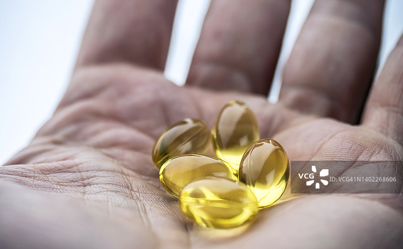 手持几粒鱼油胶囊图片素材