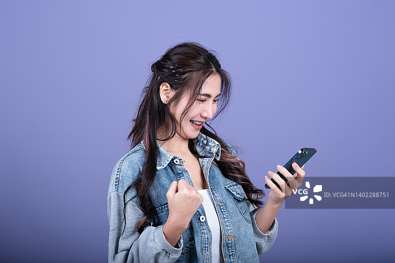 在粉红色背景上使用智能手机的女人图片素材