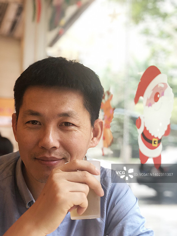 中年中国男人坐在玻璃窗旁图片素材