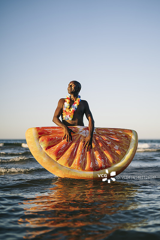 在海边度假，带着橙色游泳圈的非洲男人图片素材