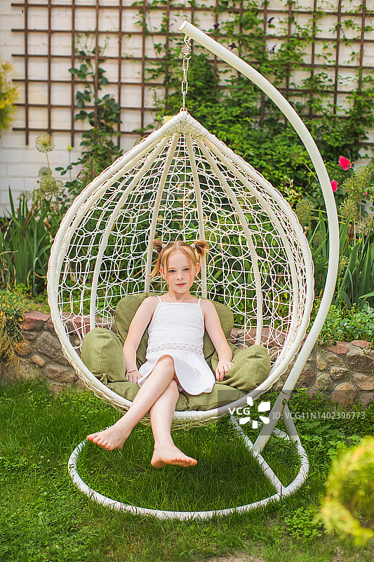 在柳条躺椅上长雀斑的红发女孩，童年夏日户外休闲图片素材