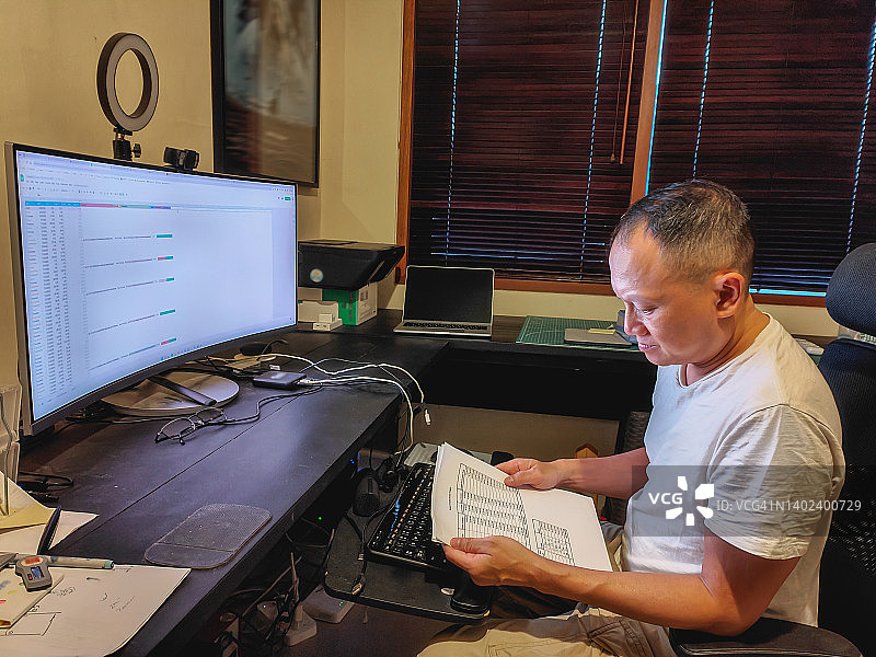 在家中办公室阅读财务报告的越南男人图片素材