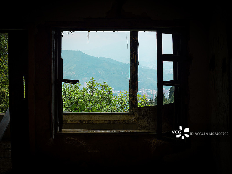 从废弃房屋潮湿的窗户看天空和山脉图片素材