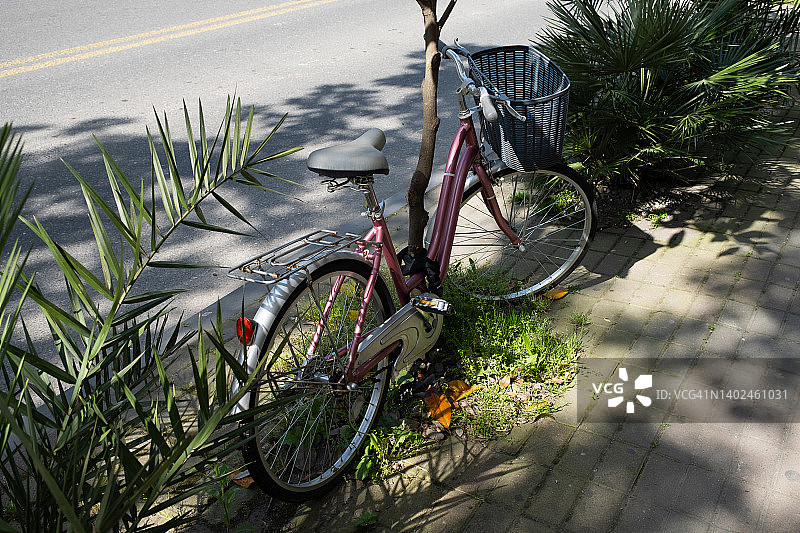 阳光明媚的夏日，格鲁吉亚街头，靠在柱子上的带篮子复古自行车图片素材