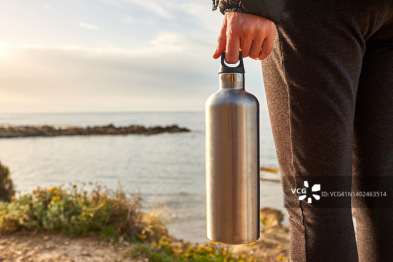不露脸的女人在山上手拿水瓶面朝大海图片素材