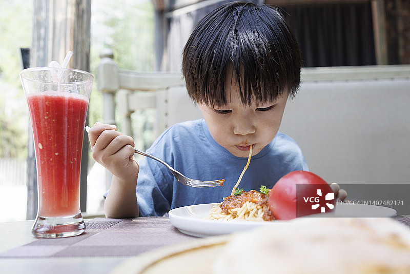 男孩在餐厅吃意大利面图片素材
