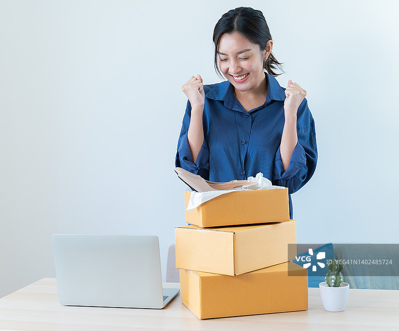 亚洲女性在家网上购物、拆包裹，感到快乐图片素材