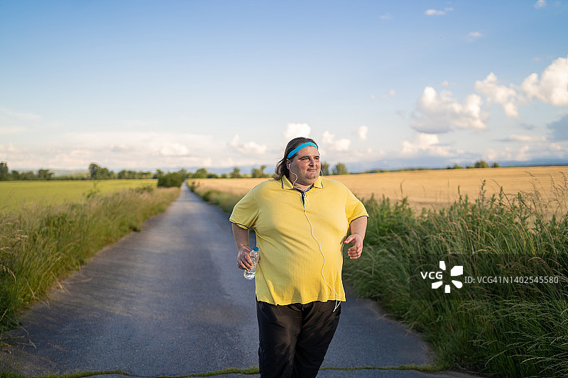 在空旷的道路上慢跑的肥胖男人图片素材