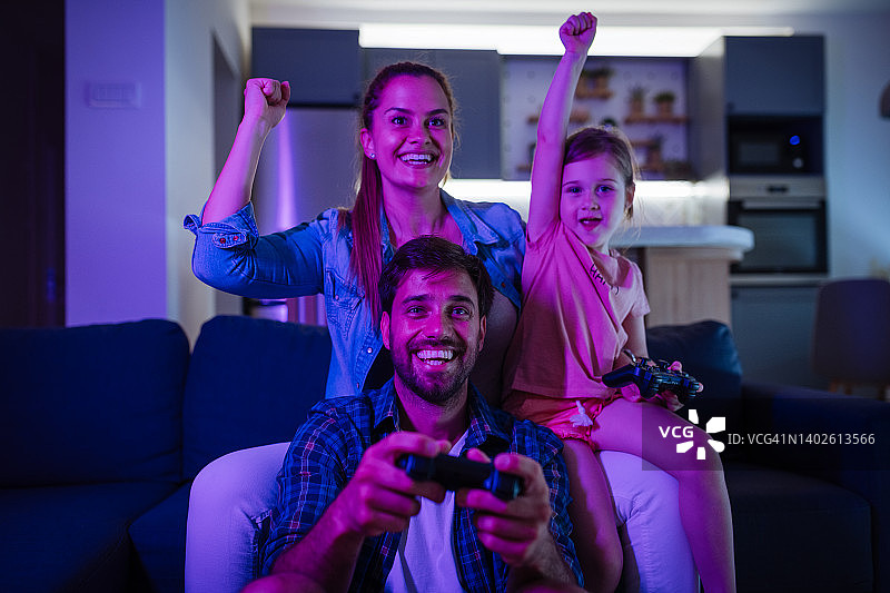 一家三口在家用遥控手柄玩电子游戏，其乐融融图片素材