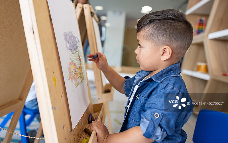 快乐的男孩在学校美术课上涂色图片素材