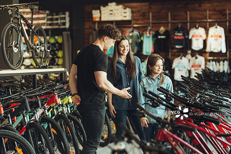 男人在自行车店向女人和她的女儿展示新自行车图片素材