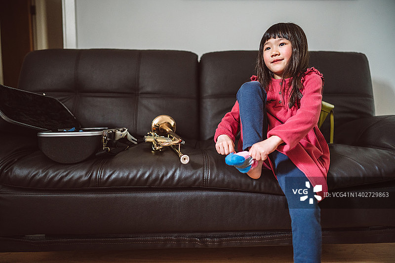 可爱的小女孩坐在家里的沙发上拉袜子图片素材