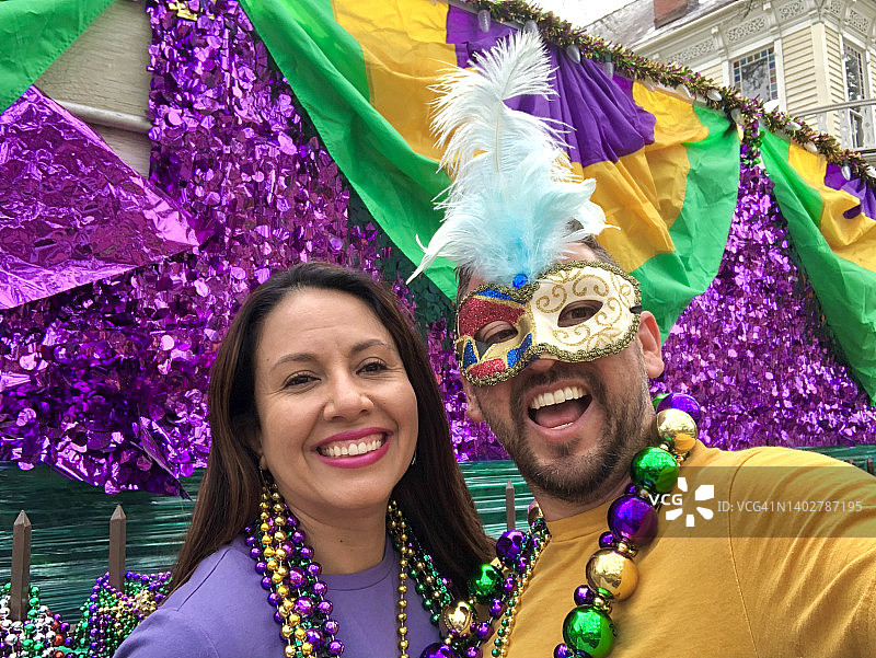 快乐的拉丁裔游客朋友/异性恋夫妇在新奥尔良庆祝狂欢节，穿着项链和面具图片素材