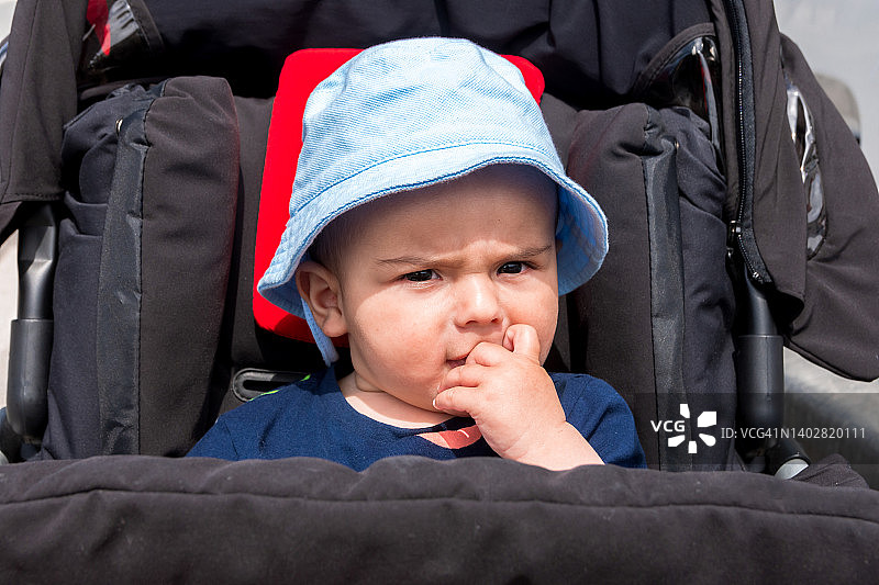 坐在婴儿车里，头戴帽子的婴儿肖像照图片素材