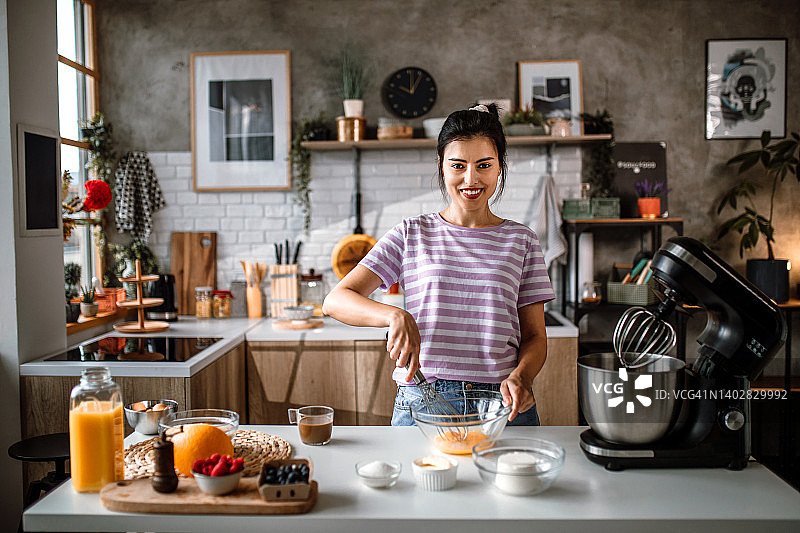 在厨房做蛋糕并看向镜头的微笑的中年妇女肖像图片素材