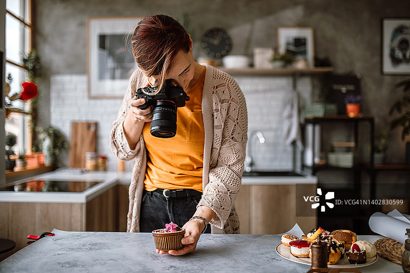 中年女糕点师在桌子背景上拍摄自制蛋糕图片素材