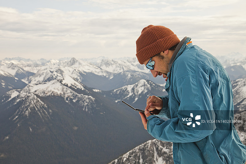 徒步旅行者在山顶上查看手机短信图片素材