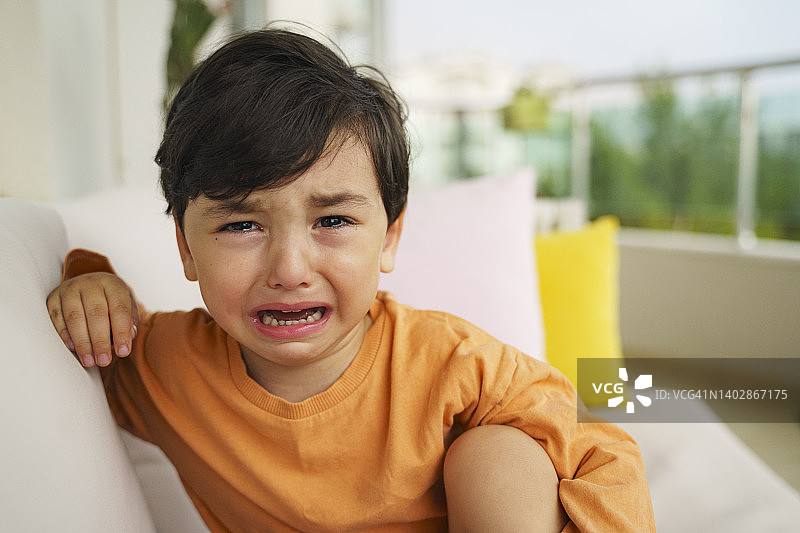 坐在阳台沙发上哭泣的无辜幼儿图片素材