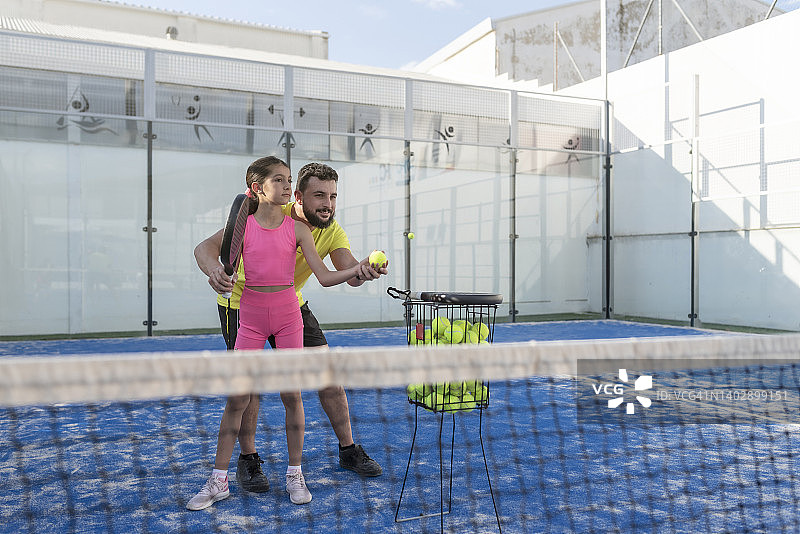 父亲教孩子们在球场上打板式网球图片素材