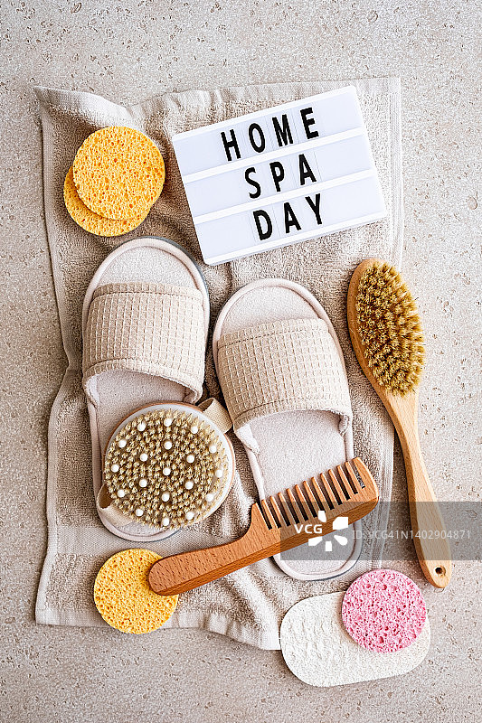 家用SPA设备（棉毛巾、木制身体刷、发刷、清洁海绵、拖鞋），用于身体和头发护理，以及带有文字“家庭SPA日”的灯箱在混凝土背景上，顶视图。可持续的生活方式。零浪费概念。图片素材
