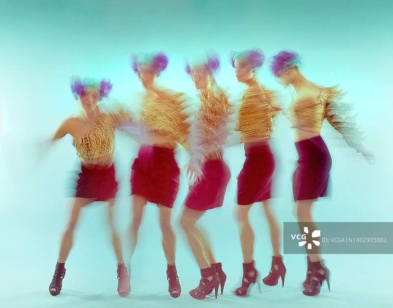 在蓝色背景上跳舞的美丽女孩，具有动态模糊和多次曝光效果图片素材