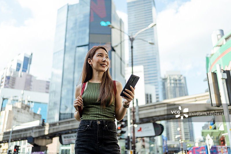 在马来西亚吉隆坡武吉免登十字路口使用智能手机的亚洲女性图片素材