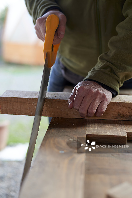 中年男人用锯子锯木头图片素材