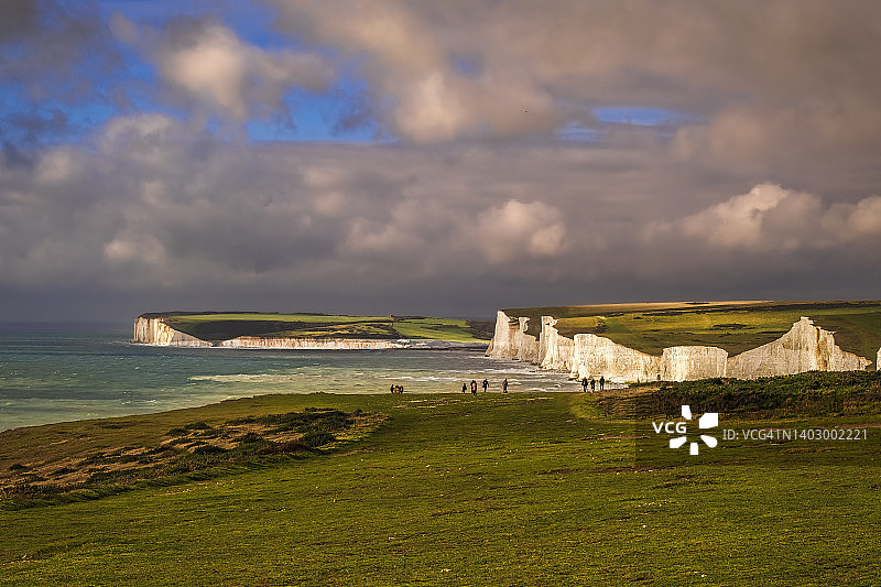 在刮风天气的英吉利海峡海岸上眺望白垩海崖；远处有小人物图片素材