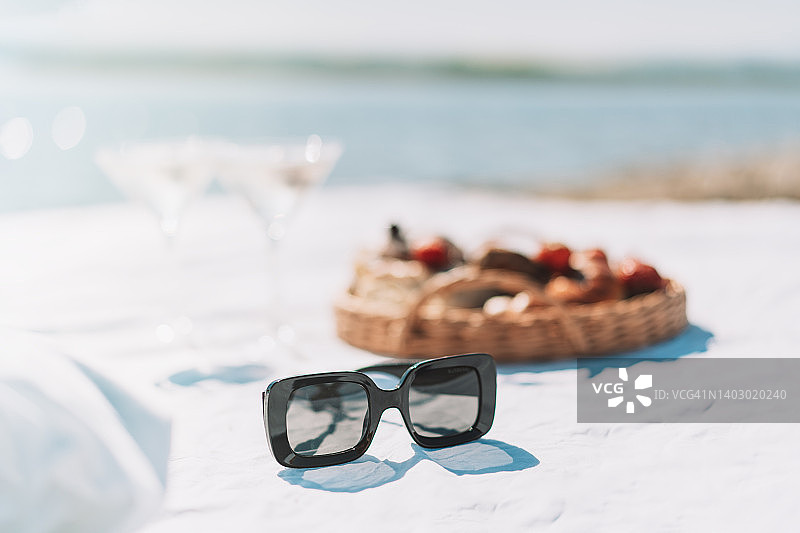 白色床单上，食物篮子和眼镜旁的太阳镜图片素材