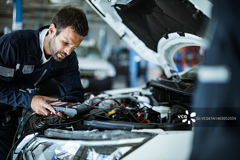 汽车修理工在修理厂使用汽车诊断工具图片素材