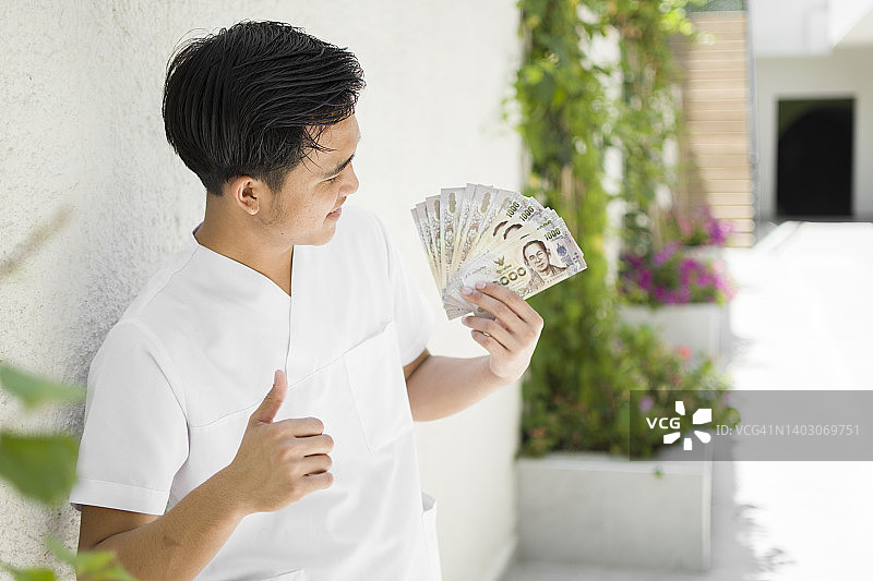 快乐的亚洲男人手持钞票图片素材