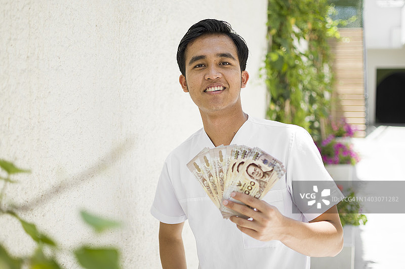 快乐的亚洲男人手持钞票图片素材