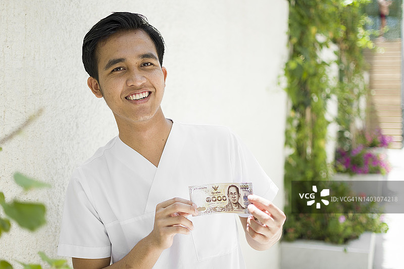 快乐的亚洲男人手持纸币图片素材