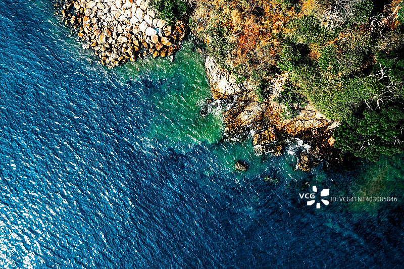 海洋波浪、沙滩、岩石海岸线和美丽森林的航拍鸟瞰图图片素材