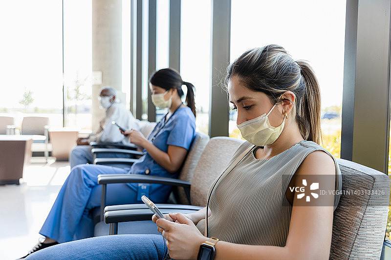 两位女士在诊所候诊室使用手机图片素材
