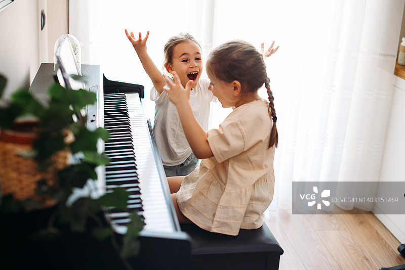 姐妹俩一起快乐地练习钢琴图片素材