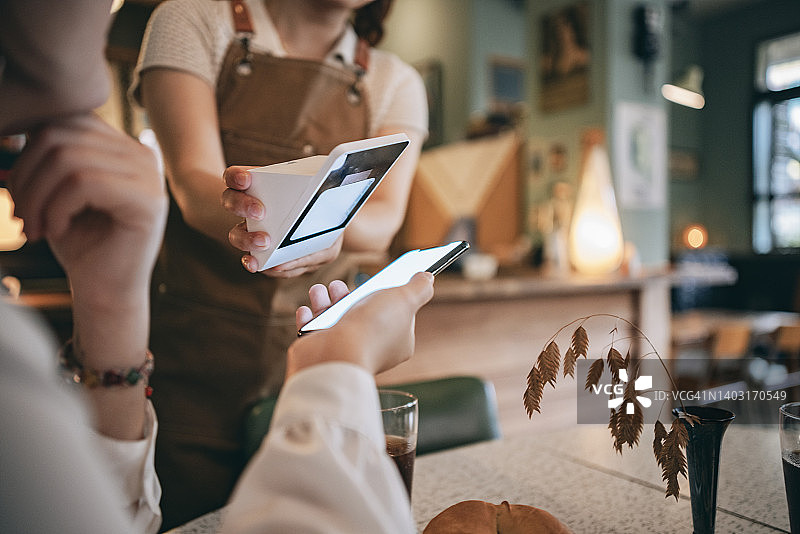 女人在咖啡馆用智能手机支付图片素材