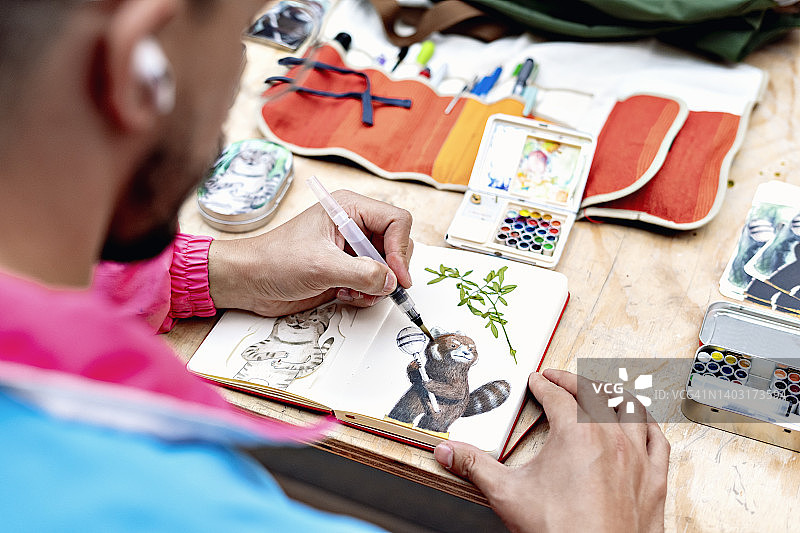 男人在笔记本上画水彩画图片素材