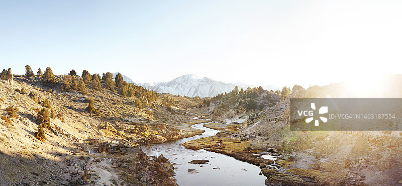 加利福尼亚热水溪地质遗址的蜿蜒温泉河与远处日落山景图片素材